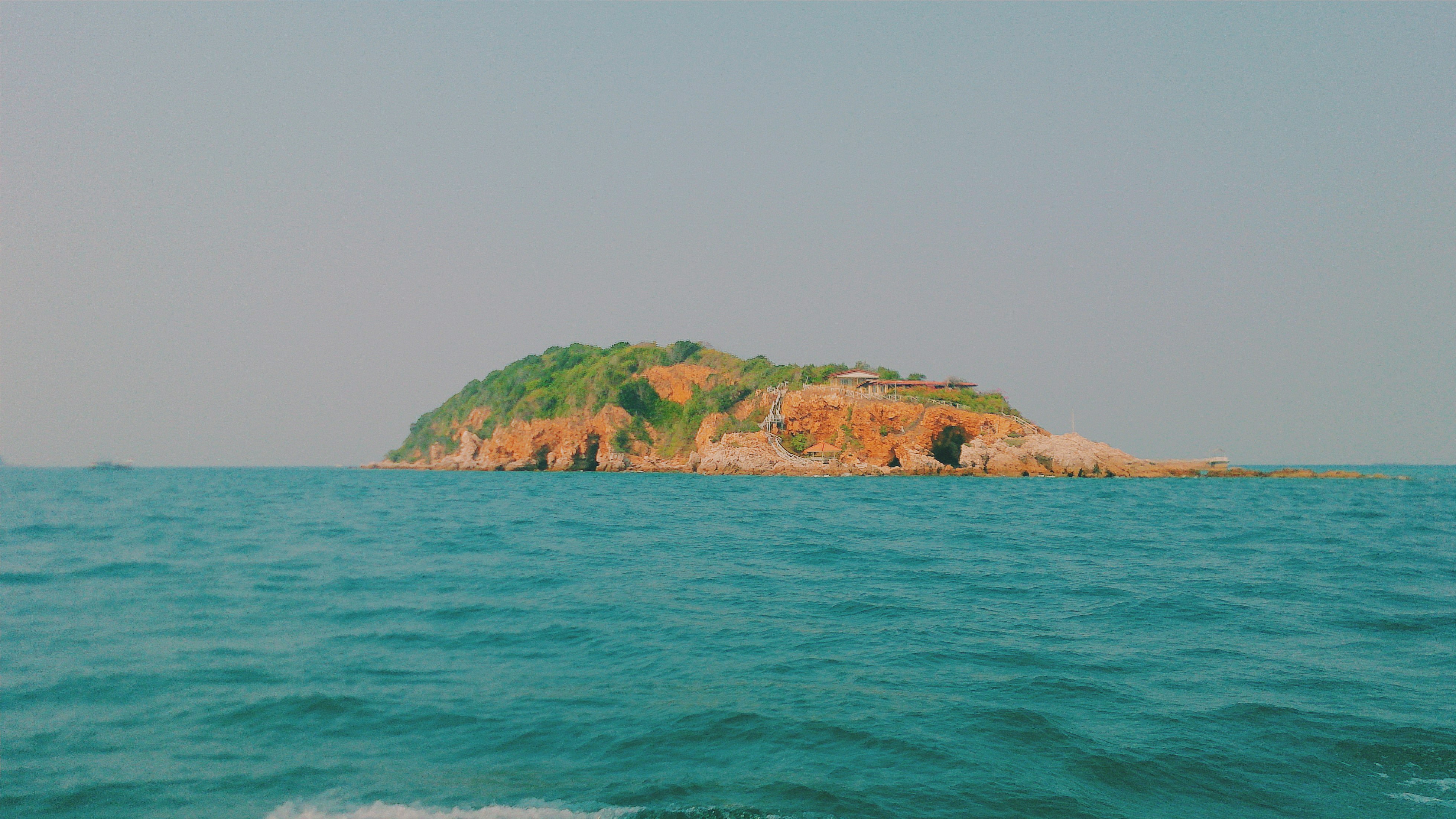 brown and green island on blue sea under white sky during daytime